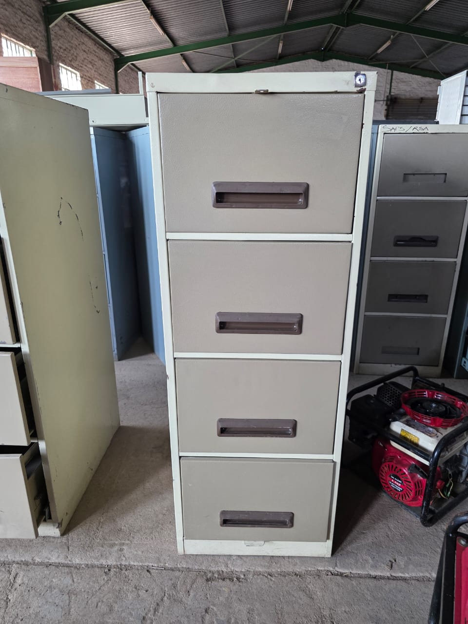 Metal filing cabinet with multiple drawers in a storage area.